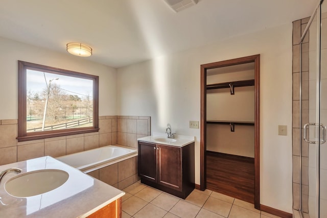 full bath featuring a walk in closet, visible vents, a stall shower, vanity, and tile patterned flooring