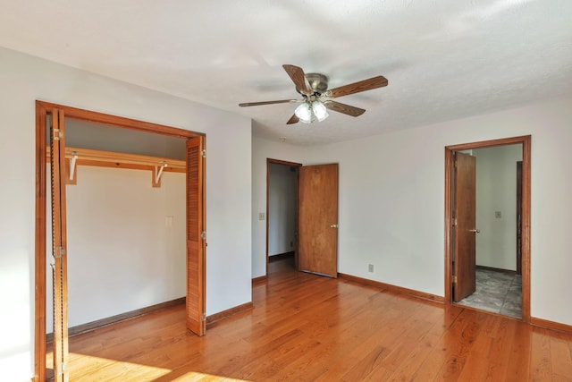 unfurnished bedroom with light wood-style floors, a closet, ceiling fan, and baseboards