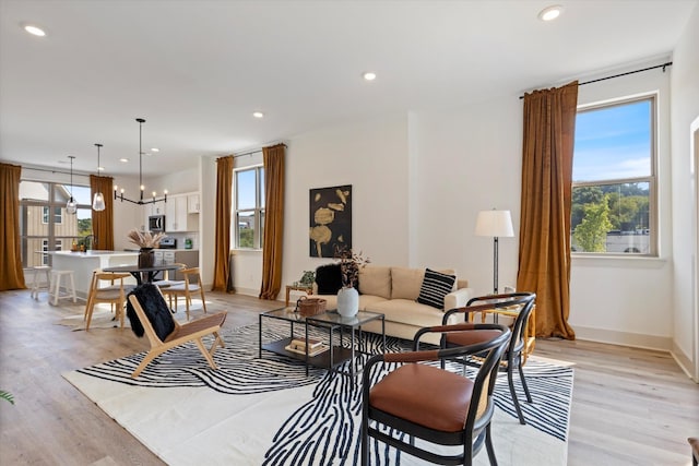 living room featuring light wood-type flooring, baseboards, a notable chandelier, and recessed lighting