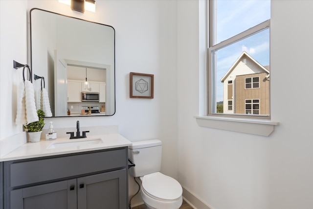 half bath with toilet, vanity, and baseboards