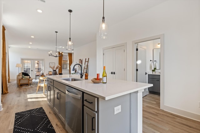 kitchen featuring a sink, light countertops, stainless steel dishwasher, and gray cabinetry