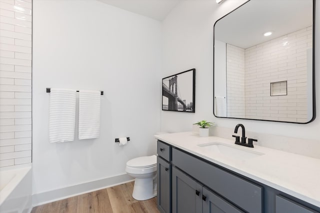 bathroom with shower / bath combination, toilet, vanity, wood finished floors, and baseboards