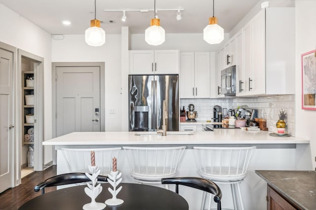 kitchen with a breakfast bar, white cabinetry, light countertops, stainless steel refrigerator with ice dispenser, and decorative light fixtures