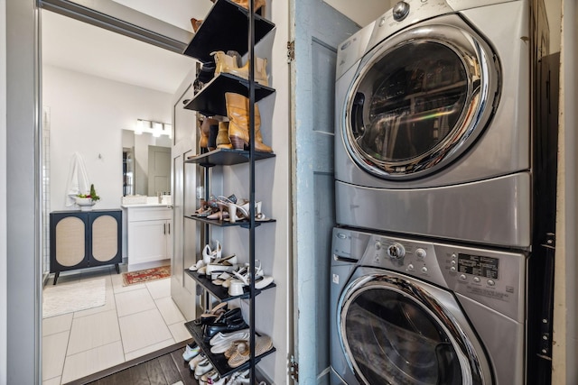 washroom with laundry area, stacked washer / drying machine, and wood finished floors