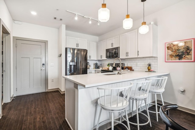 kitchen featuring decorative light fixtures, stainless steel refrigerator with ice dispenser, light countertops, white cabinets, and black microwave