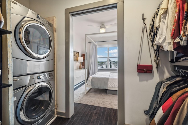 laundry area featuring dark wood-type flooring, stacked washer / drying machine, and laundry area