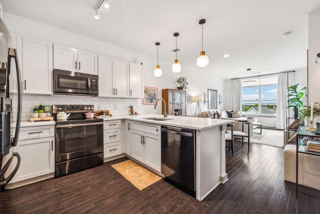 kitchen with stainless steel appliances, a peninsula, a sink, hanging light fixtures, and light countertops