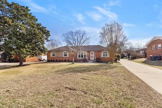 single story home featuring concrete driveway, brick siding, a front yard, and central air condition unit