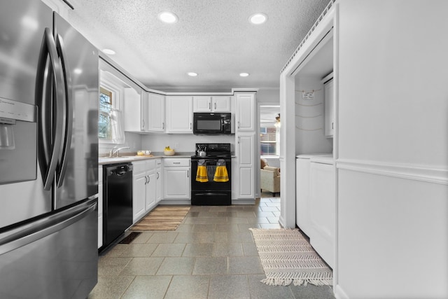 kitchen with light countertops, white cabinetry, a textured ceiling, separate washer and dryer, and black appliances