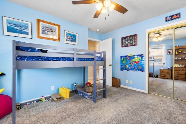 bedroom with ceiling fan, a textured ceiling, carpet flooring, baseboards, and a closet