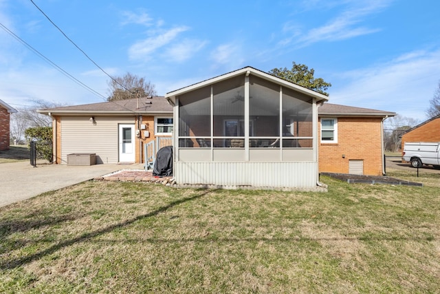 back of house with a sunroom, brick siding, and a yard