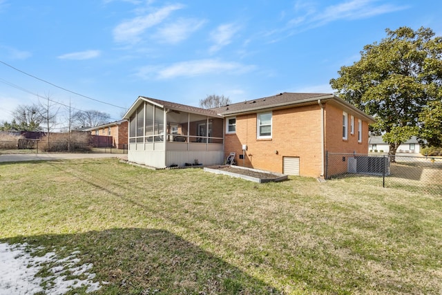 back of property with fence private yard, a sunroom, brick siding, and a lawn