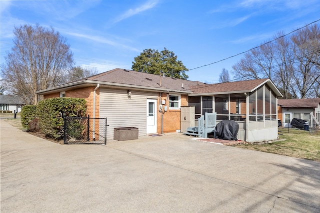 back of property featuring brick siding, fence, and a sunroom