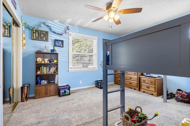 carpeted bedroom with ceiling fan, a textured ceiling, and baseboards