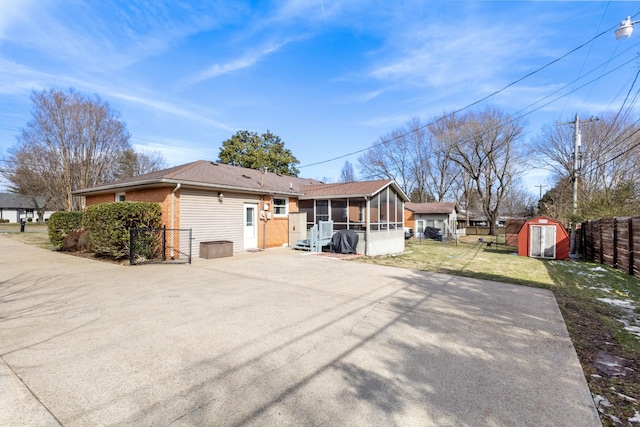 exterior space with an outbuilding, brick siding, a storage shed, a sunroom, and a fenced backyard