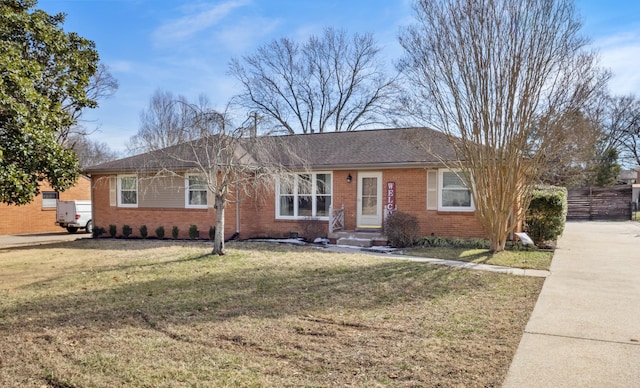 ranch-style house with a front yard, brick siding, and fence