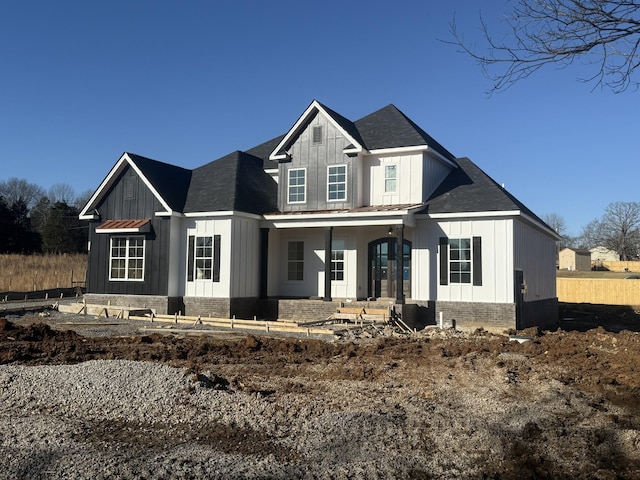 modern farmhouse style home featuring board and batten siding, covered porch, and brick siding