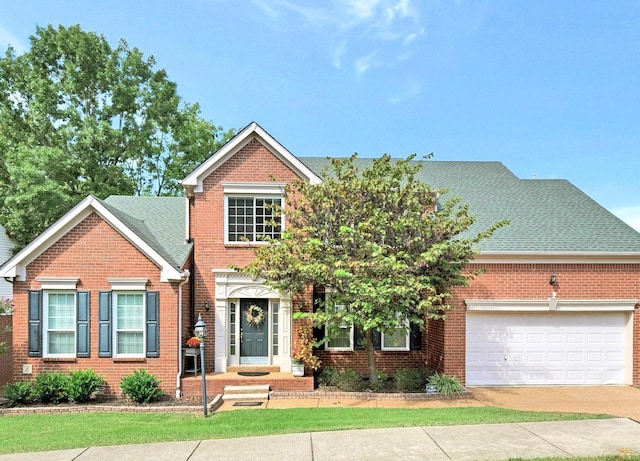 traditional-style home featuring a garage, driveway, a shingled roof, and brick siding