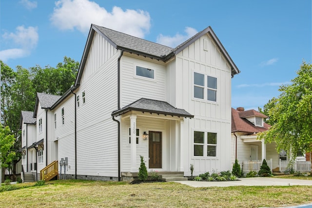 modern inspired farmhouse with entry steps, roof with shingles, a front lawn, and board and batten siding