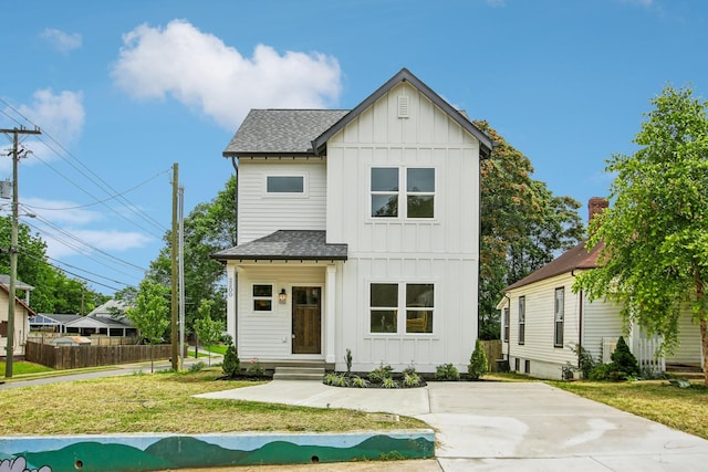 modern inspired farmhouse featuring roof with shingles, board and batten siding, and a front yard