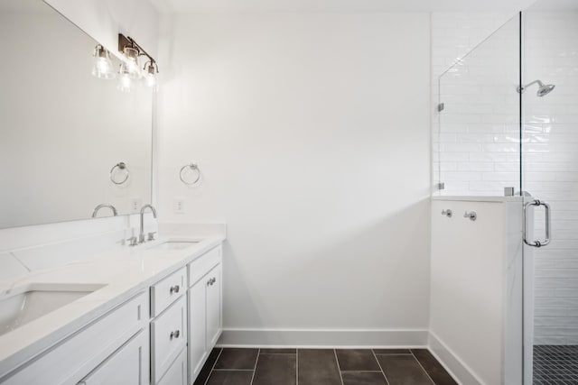 full bathroom with double vanity, a stall shower, a sink, and baseboards