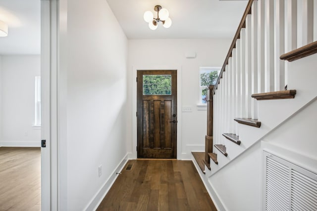 foyer entrance featuring dark wood-style floors, visible vents, baseboards, and stairs