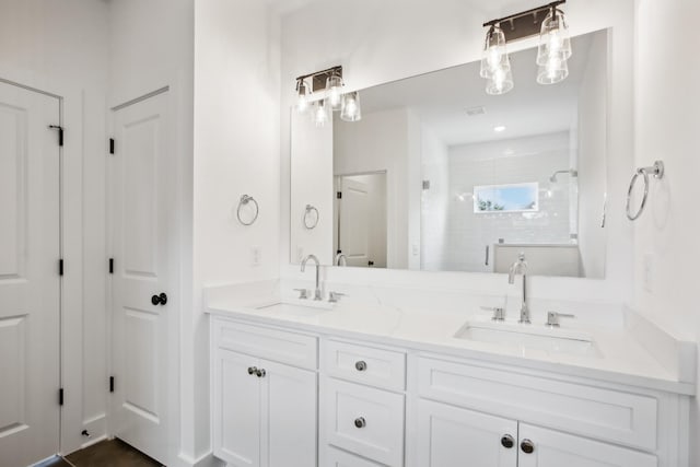 bathroom with a closet, a sink, a tile shower, and double vanity