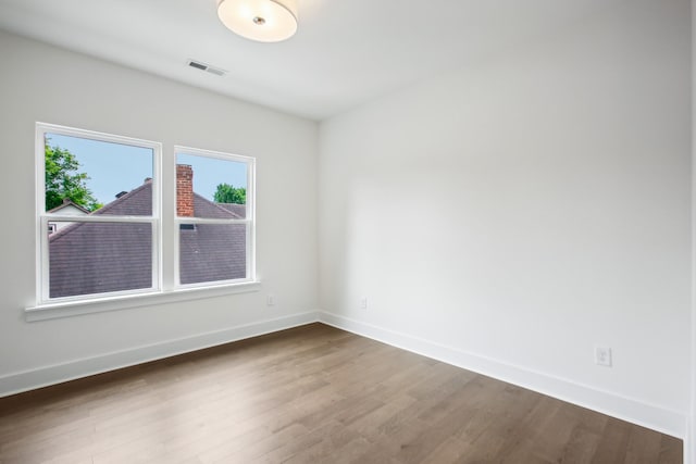 spare room featuring visible vents, baseboards, and wood finished floors