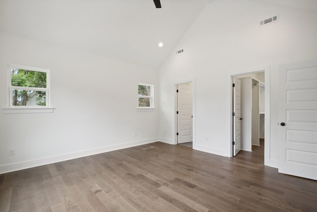 unfurnished bedroom featuring a spacious closet, dark wood finished floors, visible vents, and baseboards