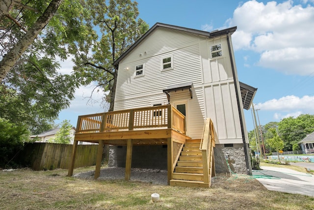 rear view of property featuring a deck, board and batten siding, stairway, and fence