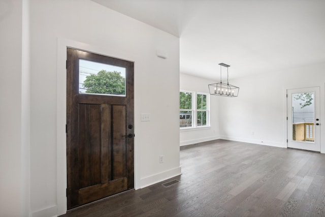 entrance foyer featuring a notable chandelier, dark wood finished floors, visible vents, and baseboards