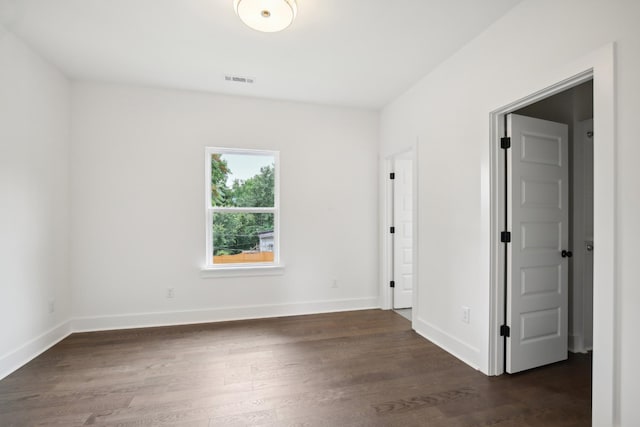 unfurnished room featuring visible vents, baseboards, and dark wood-style flooring