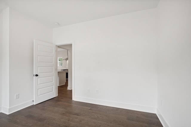 spare room featuring dark wood-type flooring and baseboards