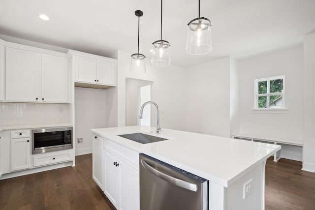 kitchen featuring stainless steel appliances, a sink, white cabinets, light countertops, and a center island with sink