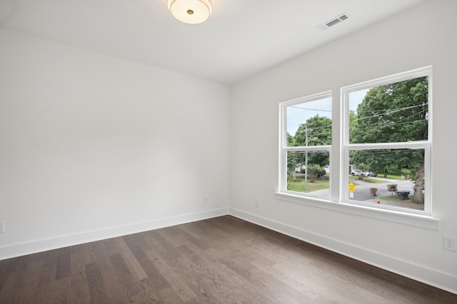 spare room featuring dark wood-style floors, visible vents, and baseboards