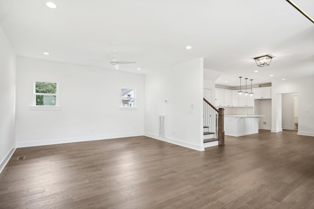 unfurnished living room featuring baseboards, stairway, dark wood-style flooring, and recessed lighting