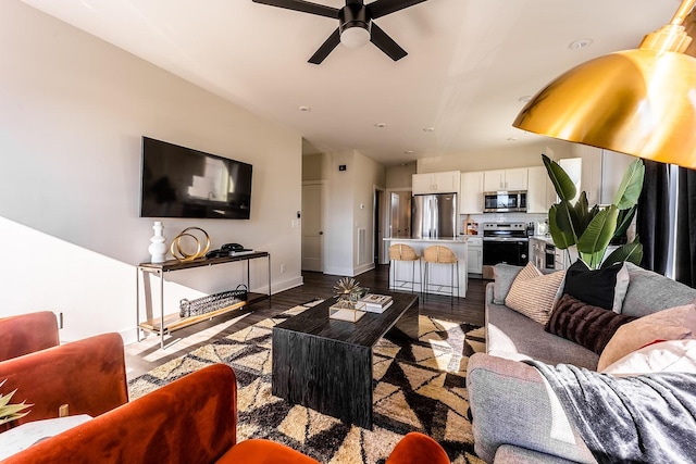 living room featuring dark wood finished floors, baseboards, and ceiling fan