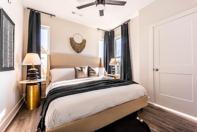 bedroom featuring ceiling fan, dark wood-style flooring, visible vents, and baseboards