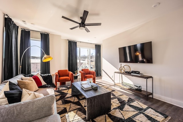 living room with ceiling fan, baseboards, and dark wood-style flooring