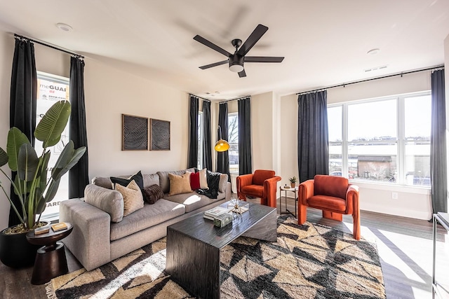 living room featuring ceiling fan, wood finished floors, visible vents, and baseboards