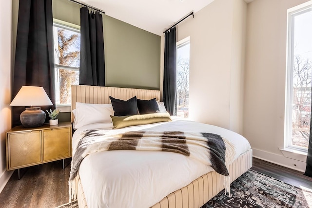 bedroom featuring dark wood-type flooring, multiple windows, and baseboards