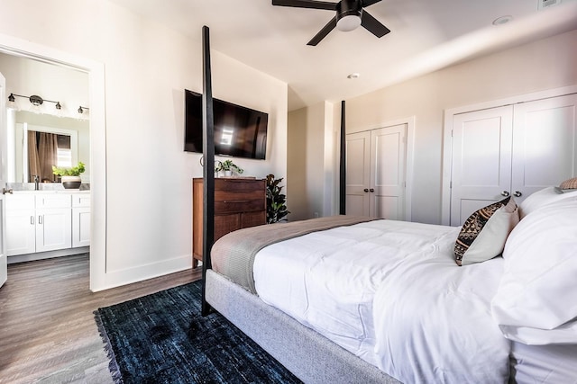 bedroom with multiple closets, visible vents, a ceiling fan, wood finished floors, and baseboards