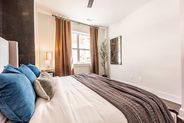 bedroom with visible vents, ceiling fan, baseboards, and wood finished floors