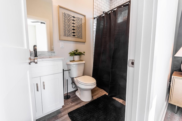 bathroom featuring toilet, a shower with curtain, wood finished floors, and vanity