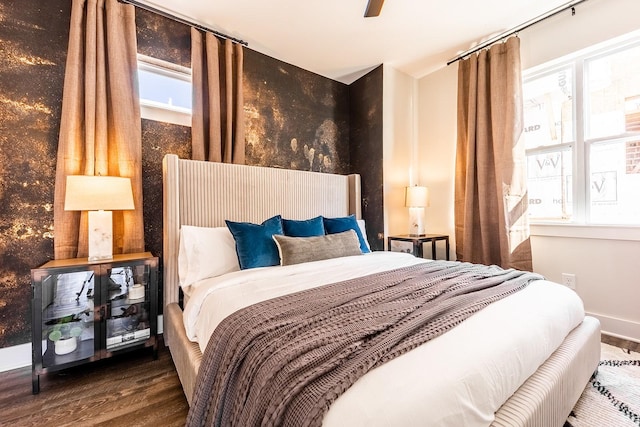 bedroom with multiple windows, baseboards, and wood finished floors