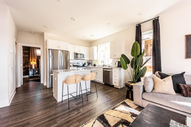 kitchen with stainless steel appliances, white cabinets, light countertops, a center island, and a kitchen bar