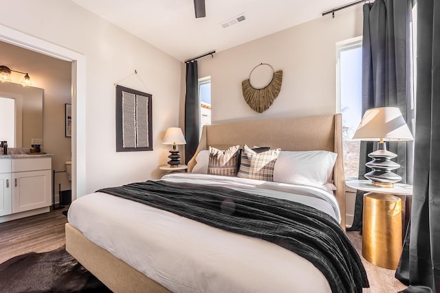 bedroom featuring visible vents, connected bathroom, and wood finished floors