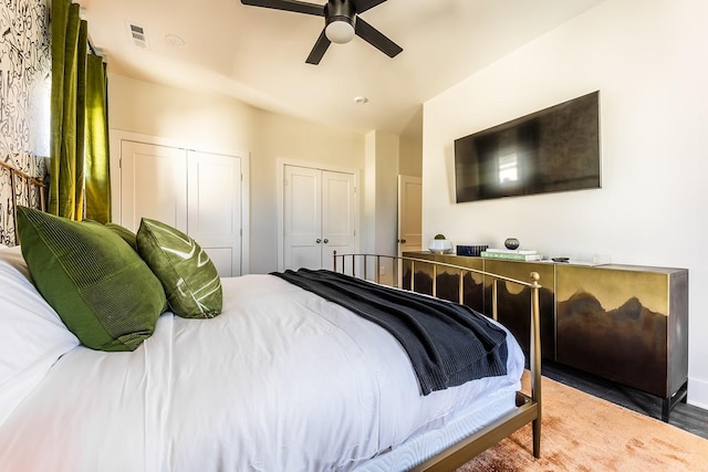 bedroom with visible vents, ceiling fan, and two closets