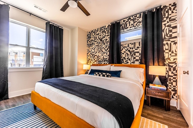 bedroom with a ceiling fan, visible vents, dark wood finished floors, and baseboards