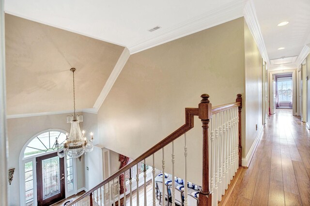 hallway featuring visible vents, light wood finished floors, an upstairs landing, and crown molding